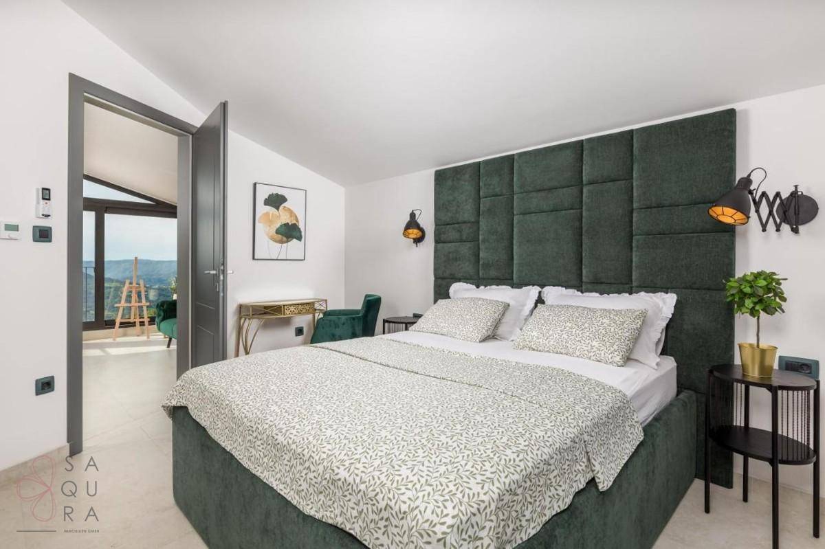Stilvolles Schlafzimmer mit großem Bett, gepolstertem Kopfteil und einem Schreibtischbereich.