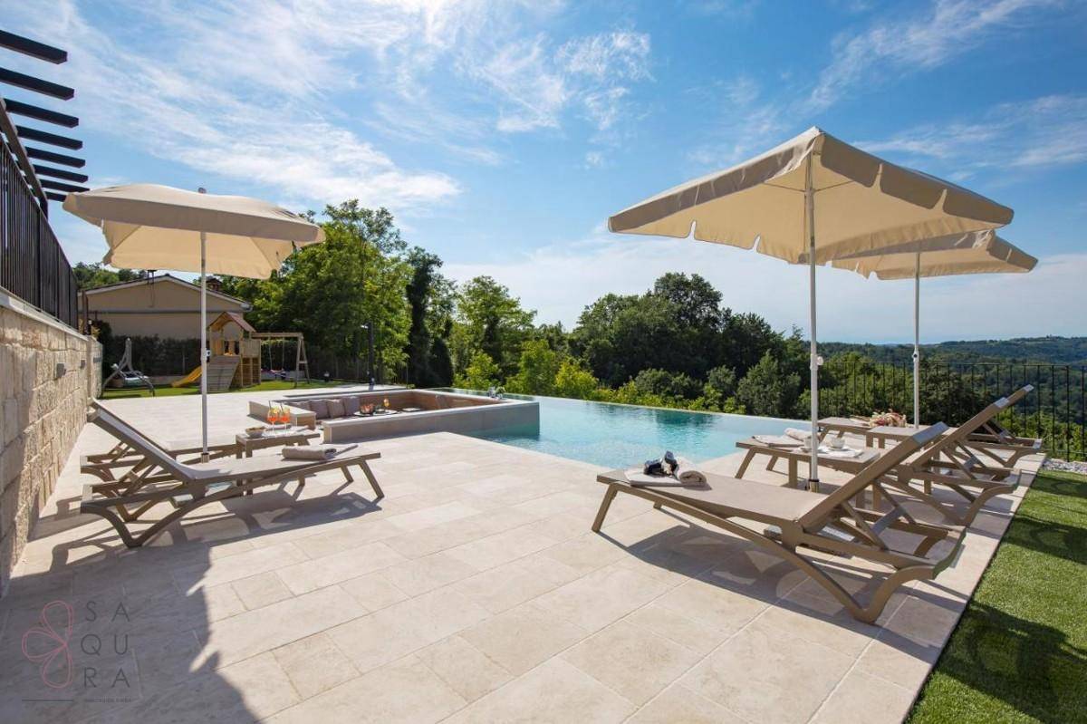 Weitläufige Poolterrasse mit Liegestühlen und Sonnenschirmen, ideal zum Entspannen in der Sonne.