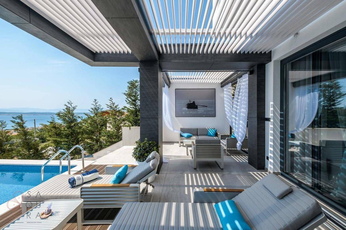 Geräumige Terrasse mit Pool, Sonnenliegen und überdachtem Loungebereich mit Meerblick.