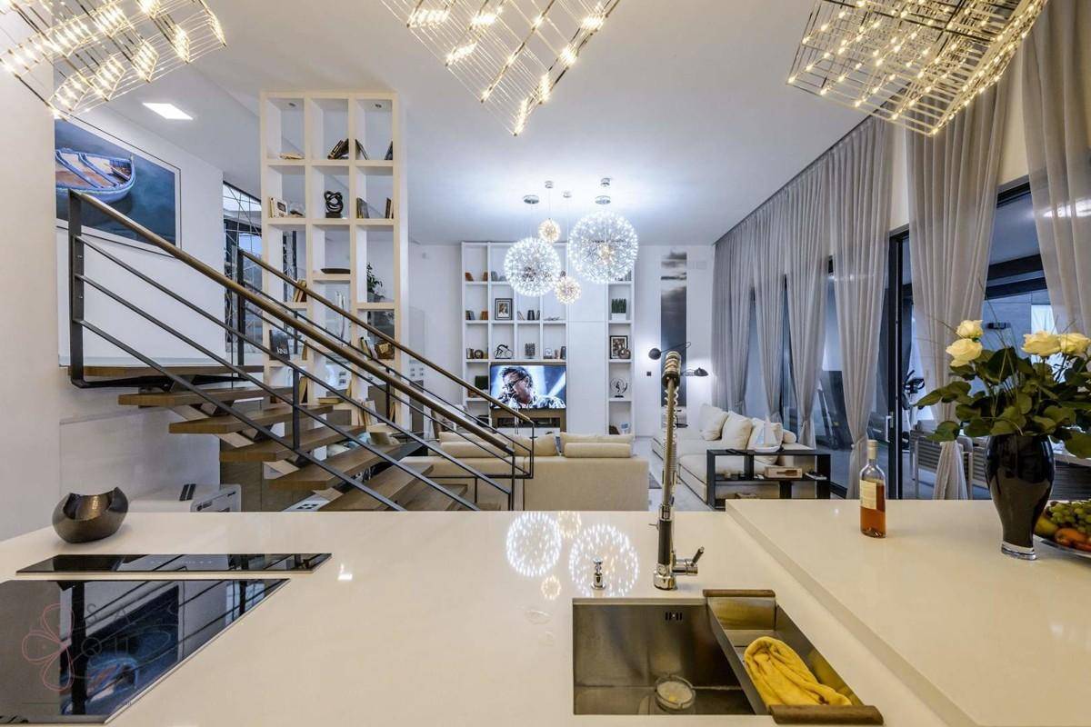Offener Wohnbereich mit moderner Küche, Treppe und stilvoller Beleuchtung.