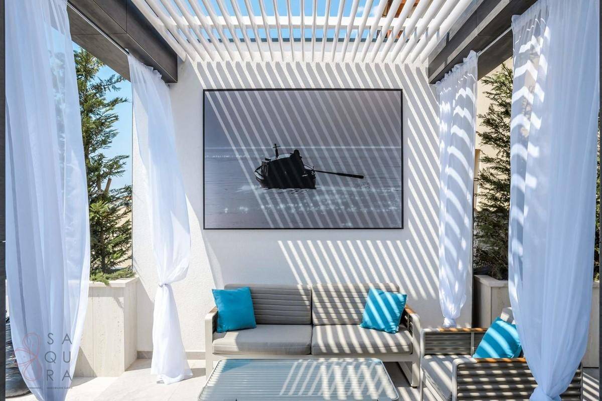 Überdachter Loungebereich auf der Terrasse mit bequemen Sofas und dekorativen Vorhängen.