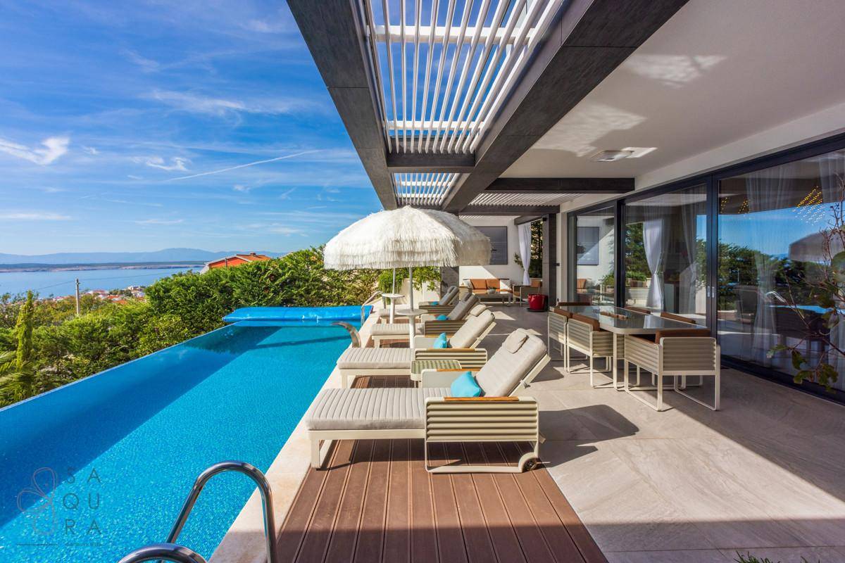 Geräumige Terrasse mit Essbereich, Sonnenliegen und Infinity-Pool mit Panoramablick auf das Meer.