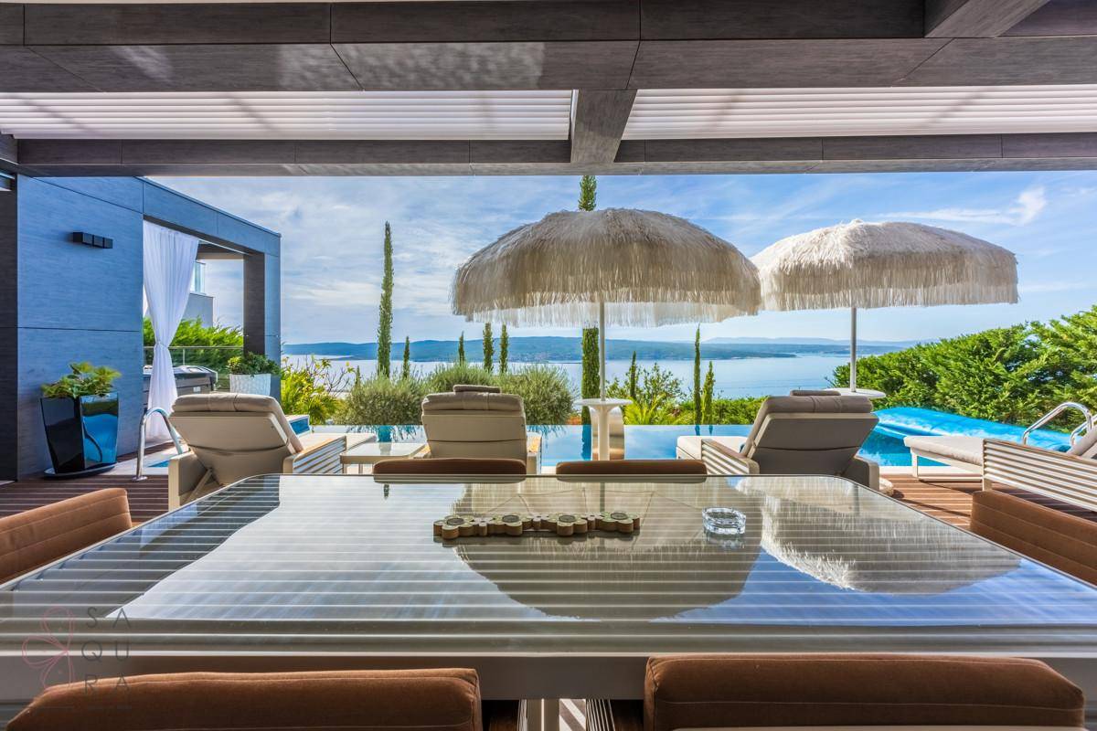 Großer Esstisch im Freien auf der Terrasse mit Blick auf den Pool und das glitzernde Meer.