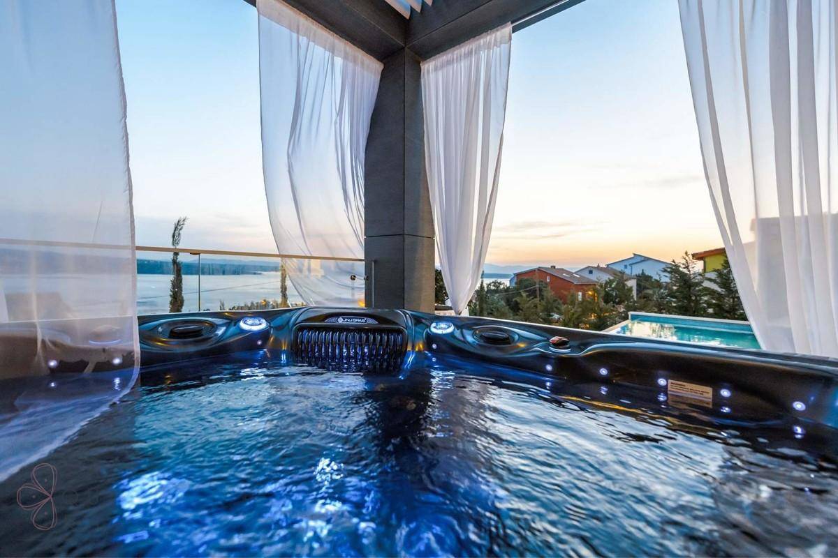 Entspannender Whirlpool auf der Terrasse mit atemberaubendem Meerblick bei Sonnenuntergang.