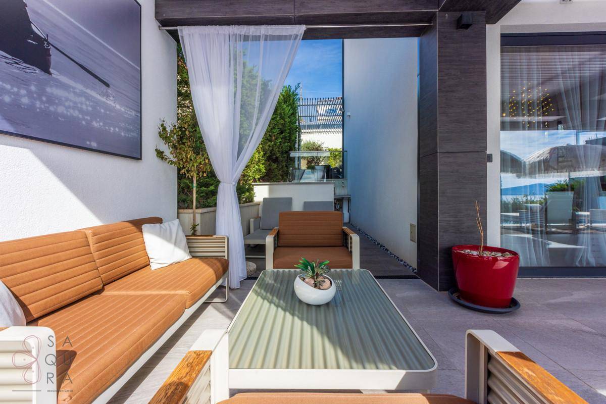 Stilvoller Loungebereich im Freien mit bequemen Sofas, Couchtisch und weißen Vorhängen.