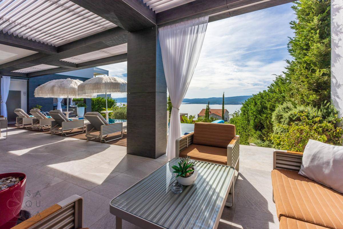 Gemütlicher Loungebereich auf der gefliesten Terrasse mit Blick auf den Pool und das Meer.