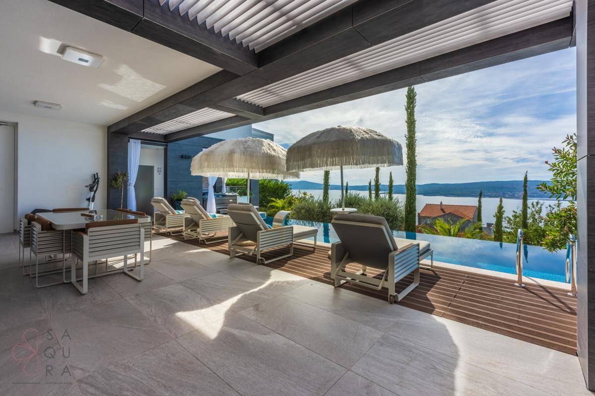 Überdachter Essbereich im Freien und Sonnenliegen am Pool mit weitem Meerblick.