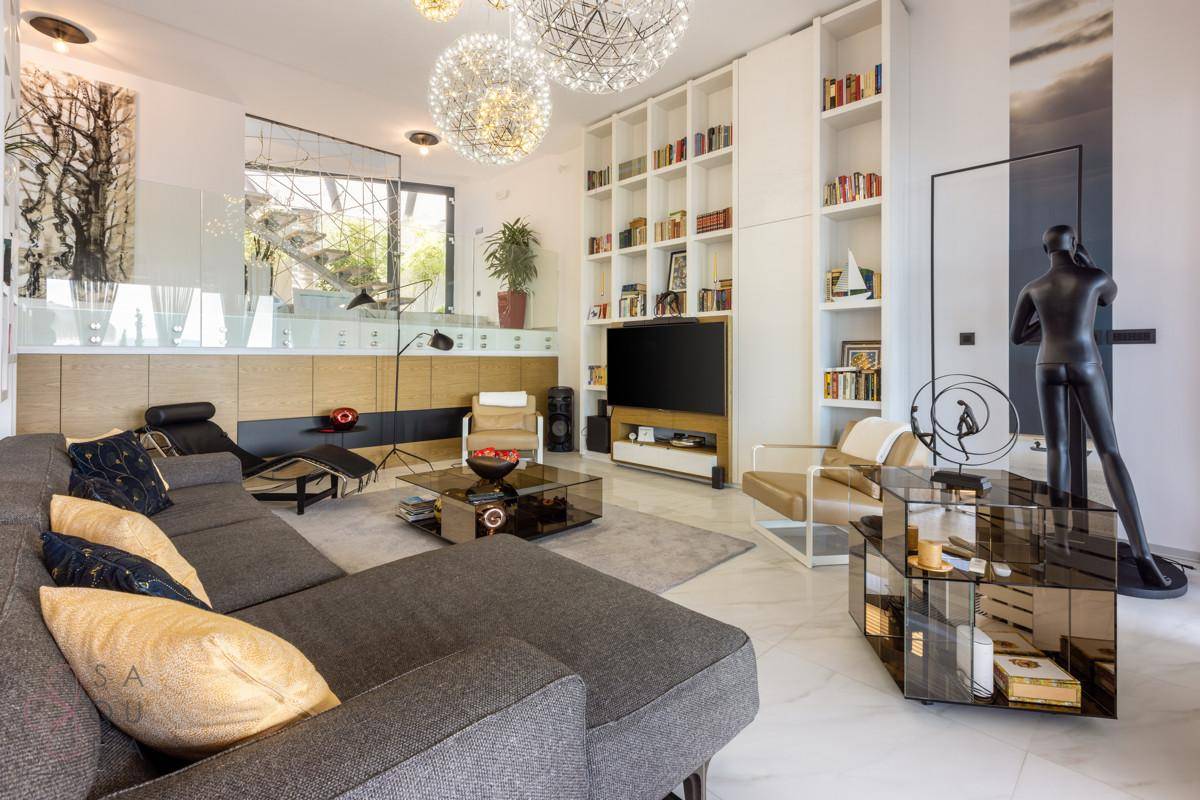 Geräumiges Wohnzimmer mit stilvoller Einrichtung, großem Bücherregal und modernen Kunstwerken.