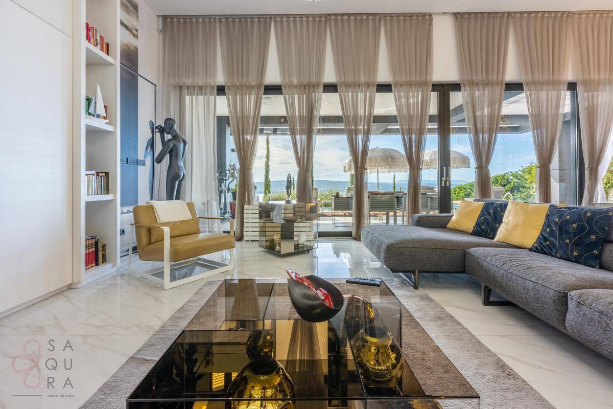 Elegantes Wohnzimmer mit raumhohen Fenstern, Meerblick und stilvoller Einrichtung.