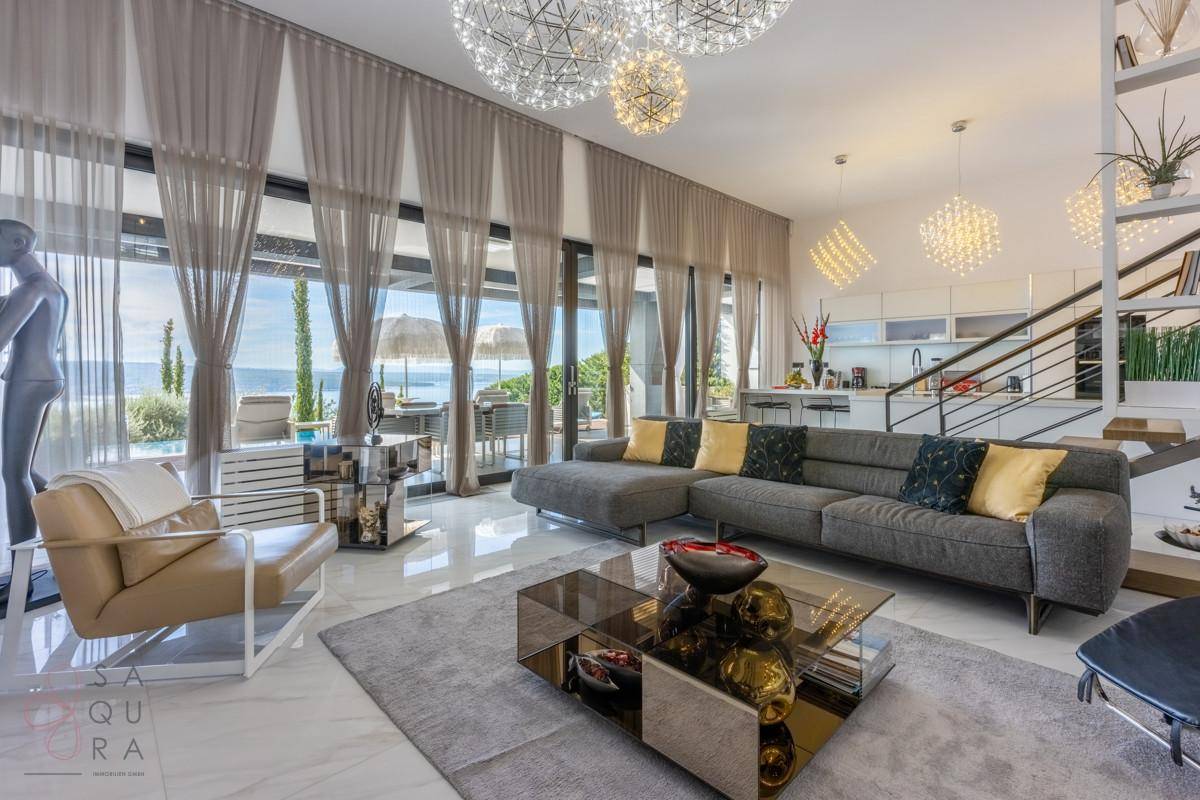 Großzügiges Wohnzimmer mit Meerblick, hohen Decken und modernen Designleuchten.