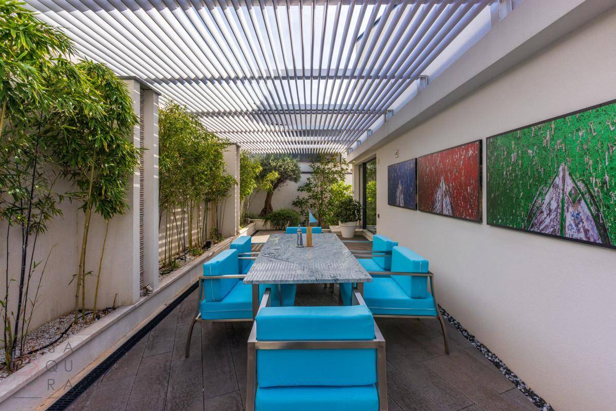Stilvolle Terrasse mit Essbereich unter einer modernen Pergola, umgeben von grünen Pflanzen.