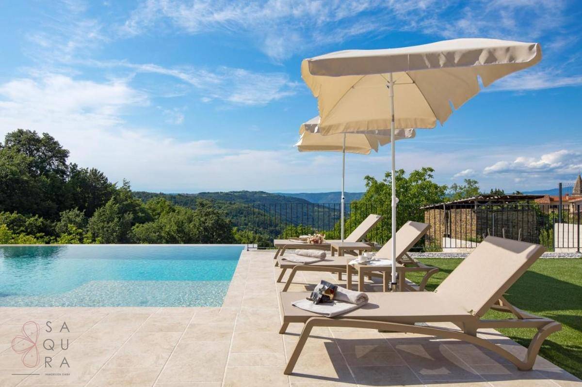 Sonniger Poolbereich mit bequemen Liegestühlen und Sonnenschirmen, mit Panoramablick.