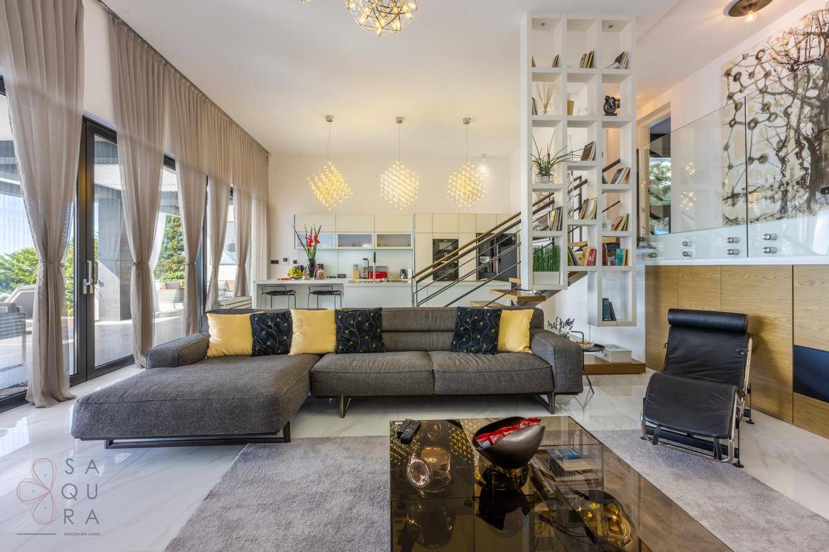 Offener Wohnbereich mit moderner Küche im Hintergrund und Zugang zur Terrasse.