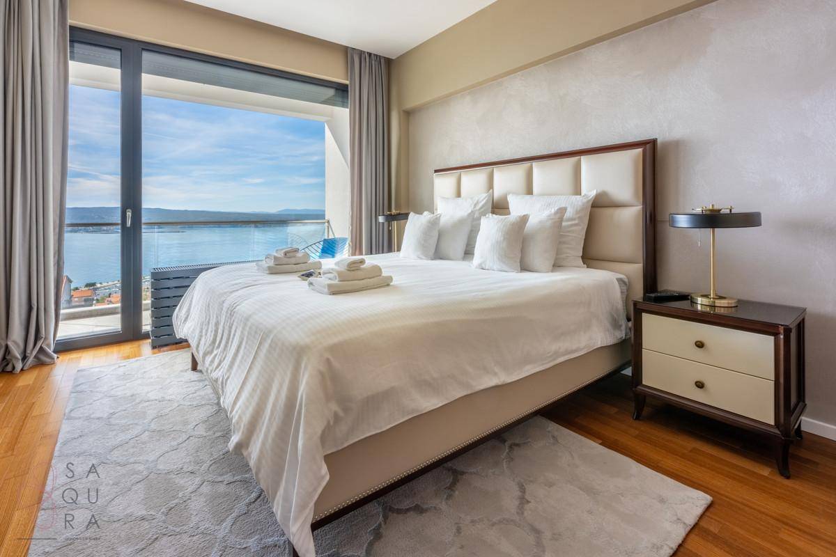 Helles Schlafzimmer mit großem Bett, Holzboden und direktem Zugang zum Balkon mit Meerblick.