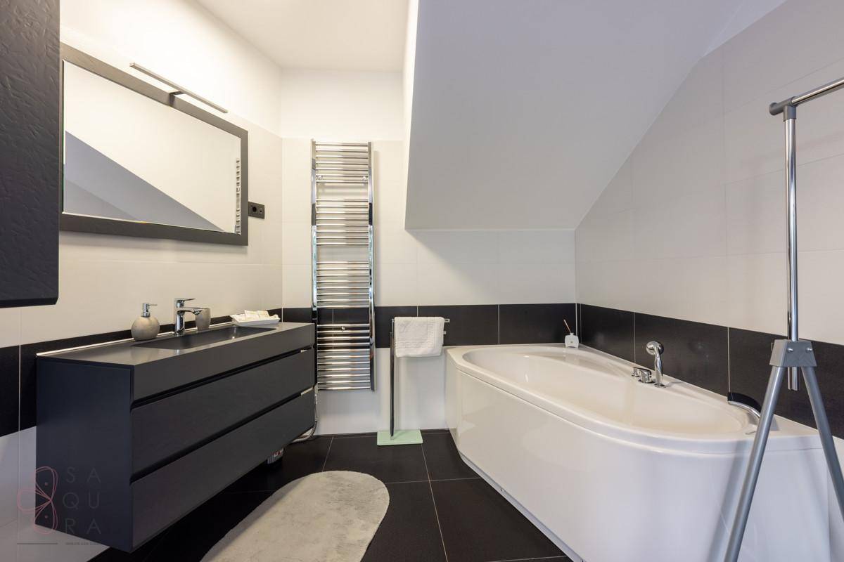 Elegantes Badezimmer mit moderner Badewanne, Doppelwaschbecken und beheiztem Handtuchhalter.