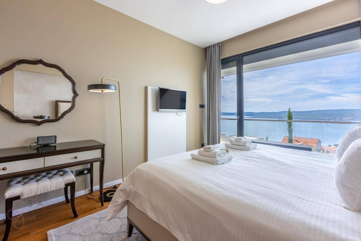 Geräumiges Schlafzimmer mit Meerblick, Schminktisch, Wandfernseher und modernem Design.