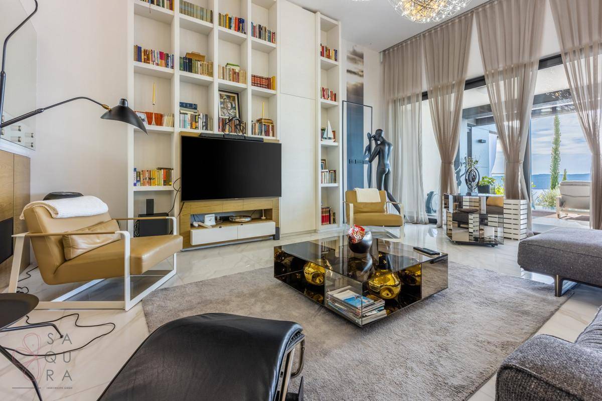 Modernes Wohnzimmer mit großem Bücherregal, Fernseher und bequemen Sitzgelegenheiten.