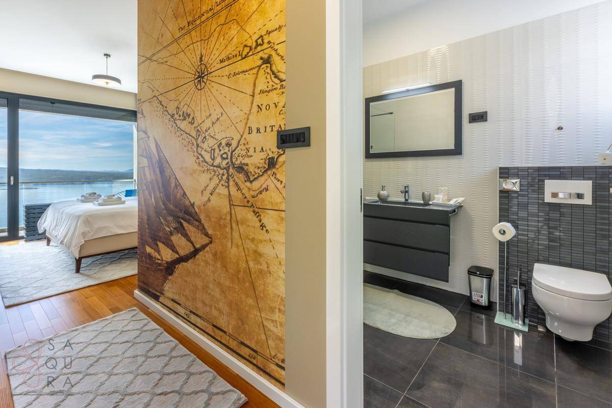 Modernes Badezimmer mit WC und Waschbecken, angrenzend an ein Schlafzimmer mit Meerblick.