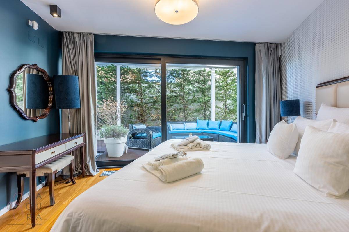 Helles Schlafzimmer mit Holzboden, Schminktisch und Zugang zu einer privaten Terrasse.