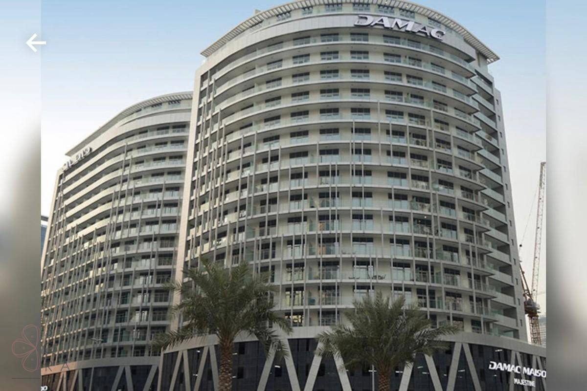Eine moderne Hochhausfassade mit vielen Balkonen und dem Schriftzug "DAMAC".