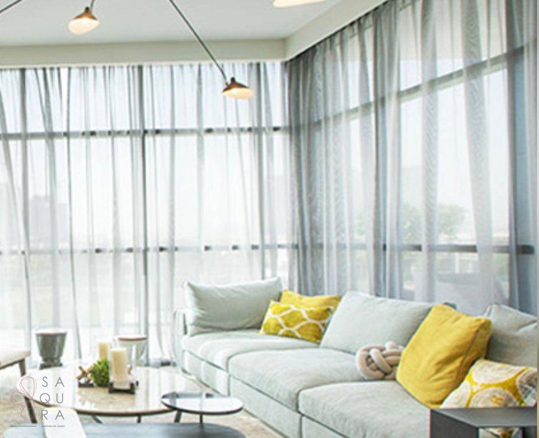 Helles, modernes Wohnzimmer mit großzügigen Fenstern, einem bequemen Sofa und gelben Akzentkissen.