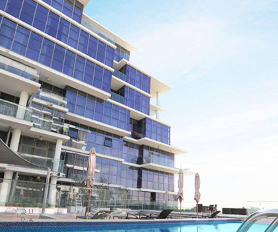 Modernes Gebäude mit blauen Glasfassaden und einem einladenden Poolbereich mit Liegestühlen.