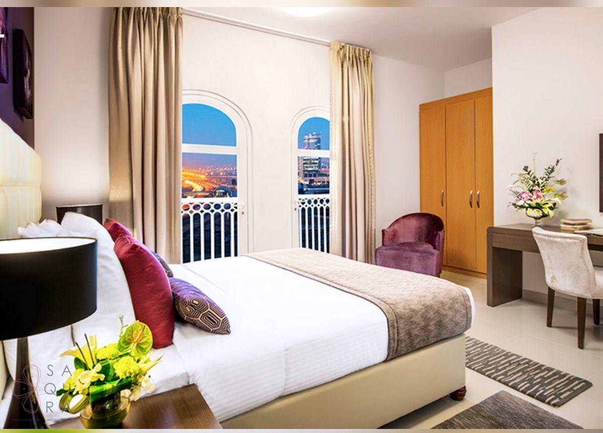Helles Schlafzimmer mit großem Bett, eleganten Vorhängen und Bogenfenstern mit Stadtblick.