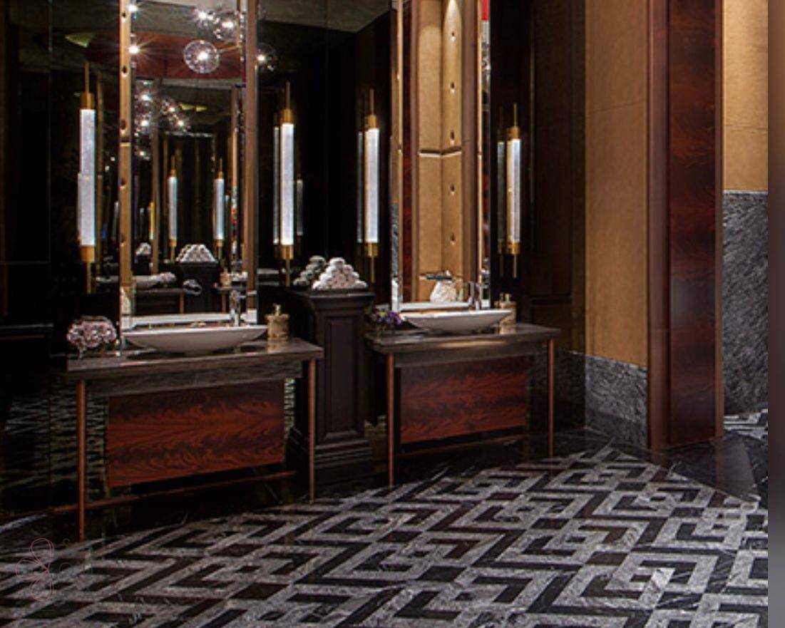 Elegantes Badezimmer mit dunklen Holzwaschtischen, Marmor und geometrischem Fliesenboden.