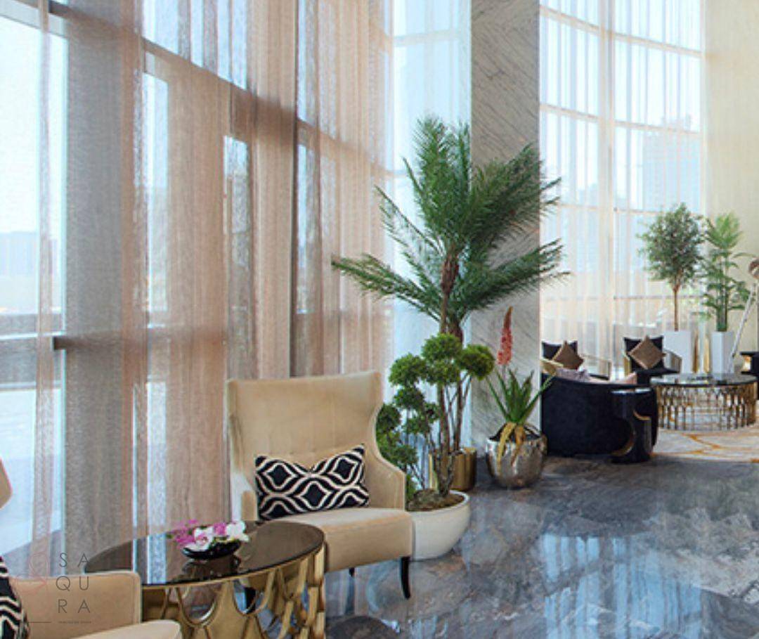 Helle Lobby mit hohen Fenstern, Pflanzen und luxuriösen Sitzbereichen.