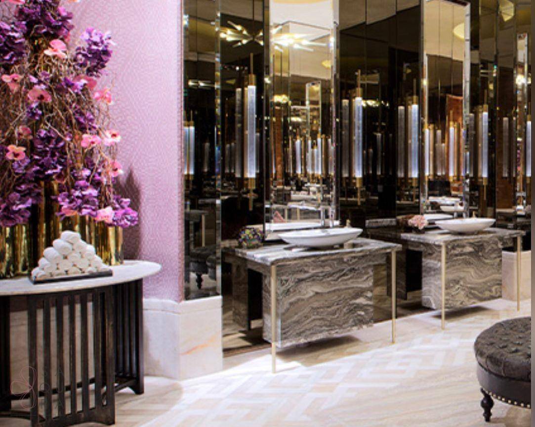 Luxuriöses Badezimmer mit mehreren Waschbecken, Marmoroberflächen und eleganten Spiegeln.