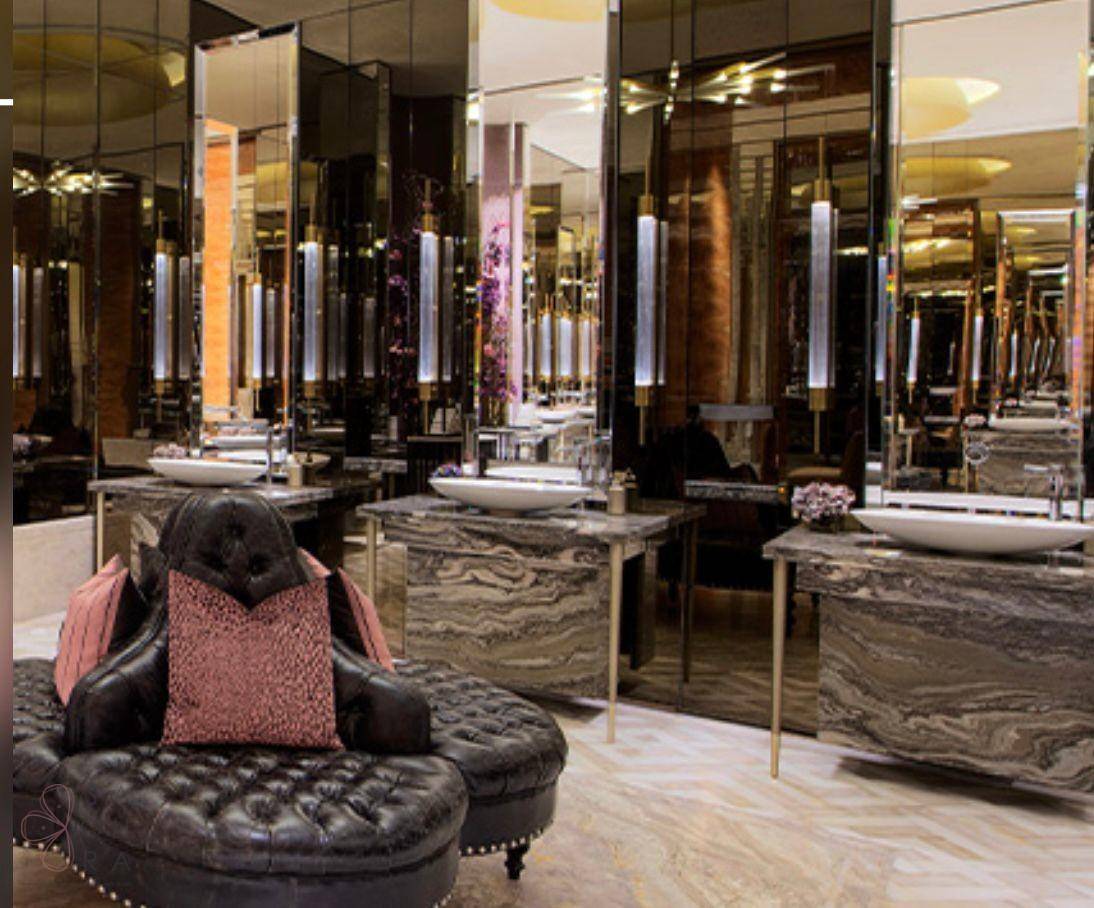 Exklusives Badezimmer mit doppelten Waschbecken, Marmor und einem Chesterfield-Sessel.