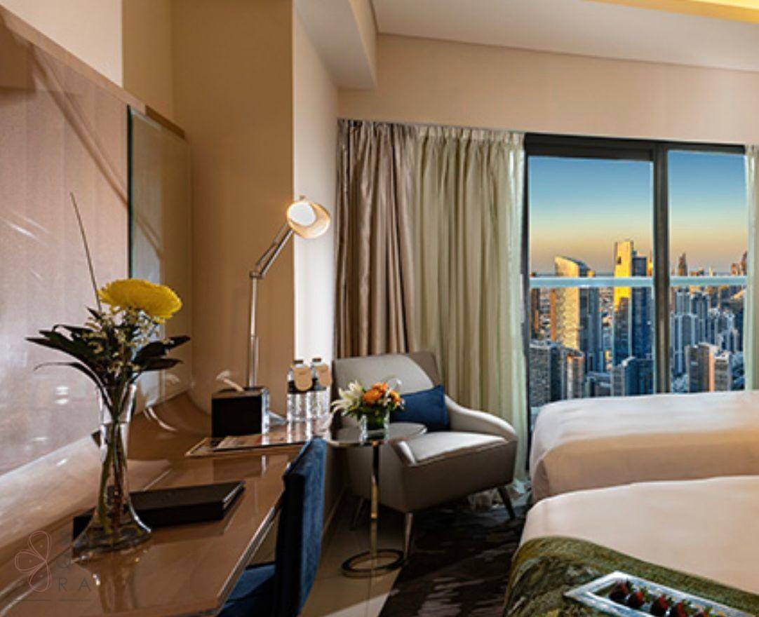 Schlafzimmer mit zwei Betten, Schreibtisch und Panoramablick auf die Stadt.