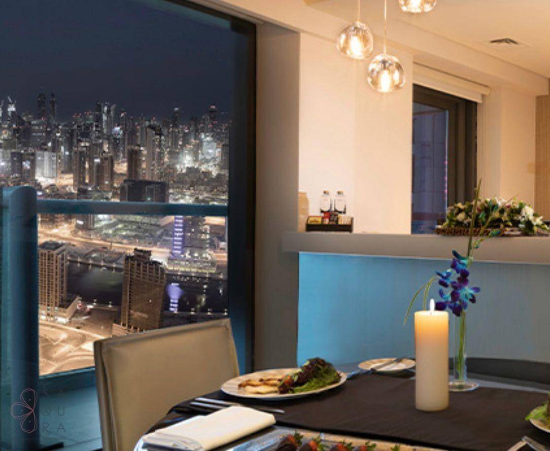 Eleganter Essbereich mit Stadtblick bei Nacht, gedecktem Tisch und stimmungsvoller Beleuchtung.