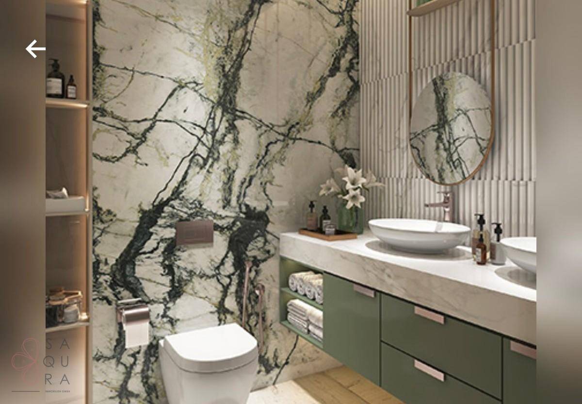 Luxuriöses Badezimmer mit grüner Marmorwand, modernem Waschbecken und wandhängender Toilette.