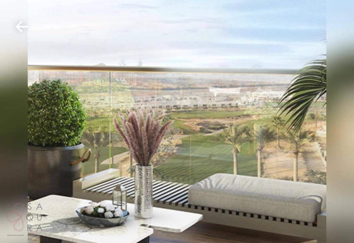 Möblierter Balkon mit Glasgeländer und Panoramablick auf einen Golfplatz.