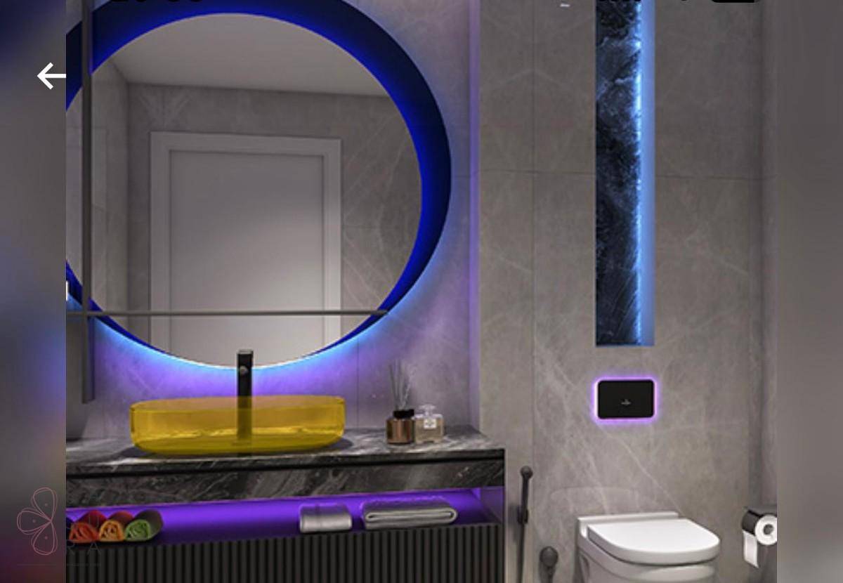 Modernes Badezimmer mit beleuchtetem Rundspiegel, gelbem Waschbecken und Wand-WC.