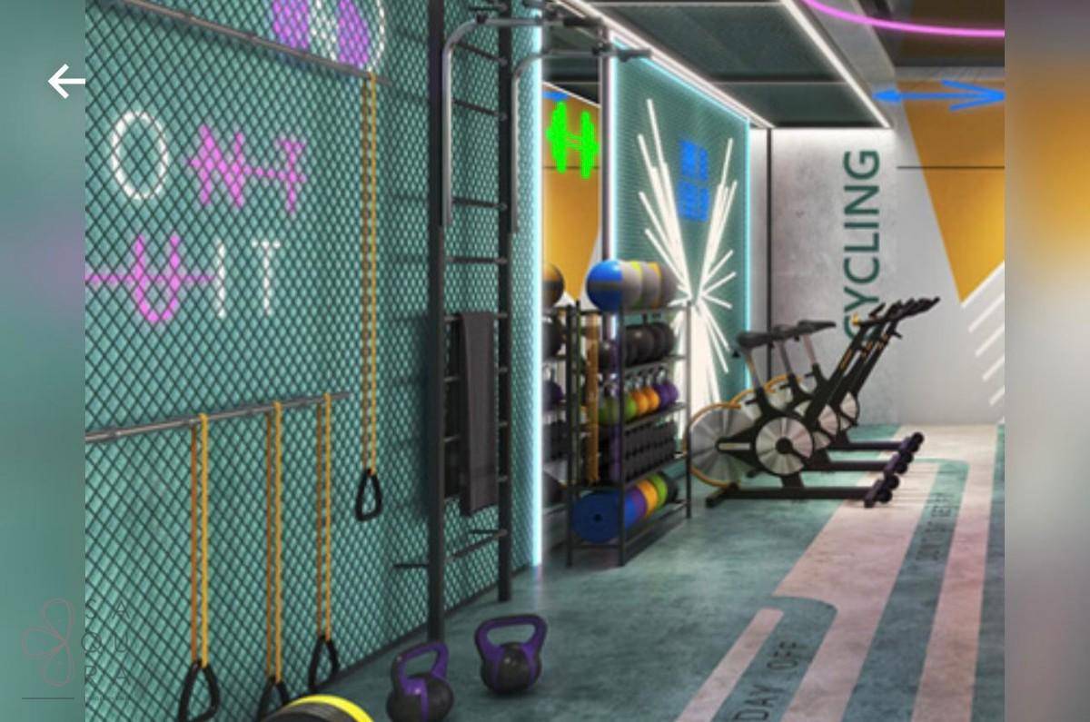 Moderner Fitnessraum mit verschiedenen Trainingsgeräten und farbiger Beleuchtung.