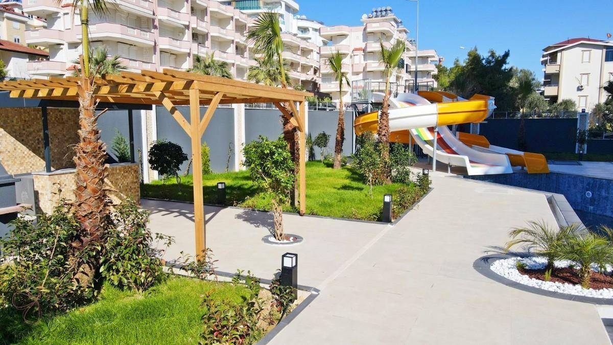 Attraktiver Poolbereich mit Wasserrutschen, Pergola und tropischen Pflanzen im Garten.