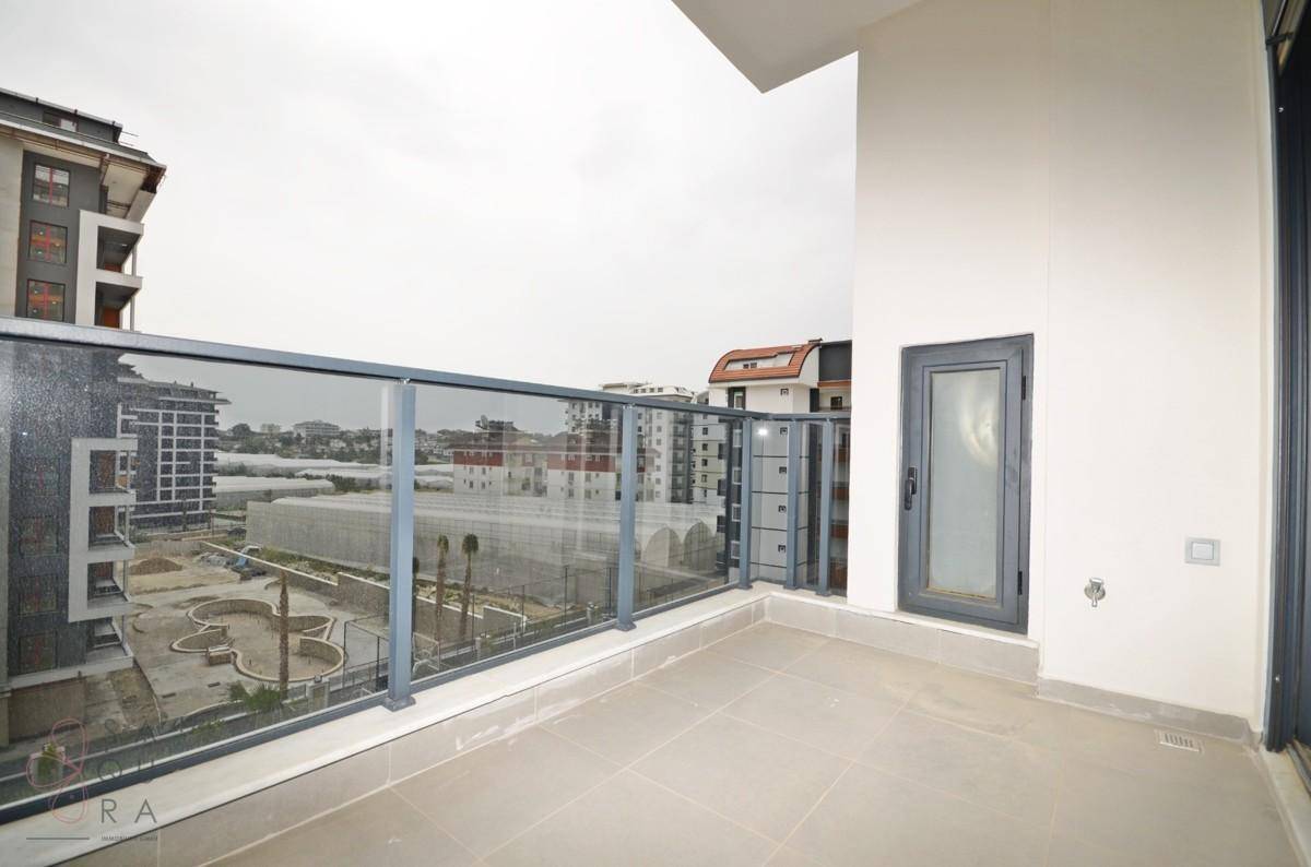 Geräumiger Balkon mit Glasgeländer und Blick auf die umliegenden Gebäude und Grünflächen.