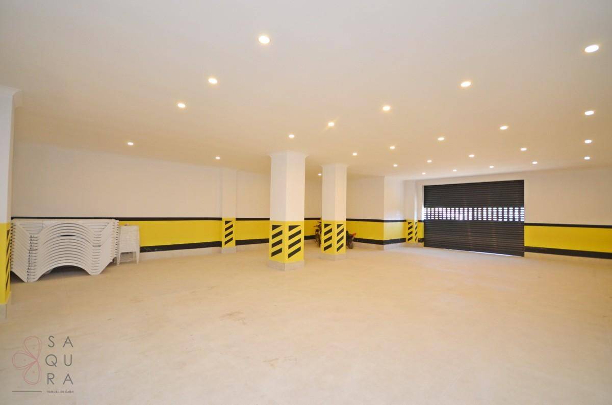 Geräumige Tiefgarage mit hellen Wänden, Säulen und einem Rolltor.