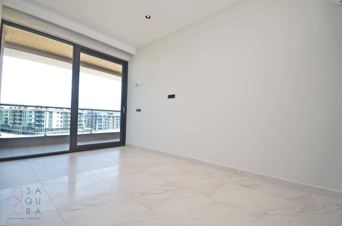 Helles Schlafzimmer mit Fliesenboden und großem Schiebefenster zum Balkon mit Stadtblick.