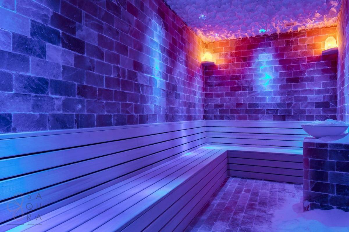 Salzraum mit beleuchteten Ziegelwänden und Holzbänken für therapeutische Zwecke.