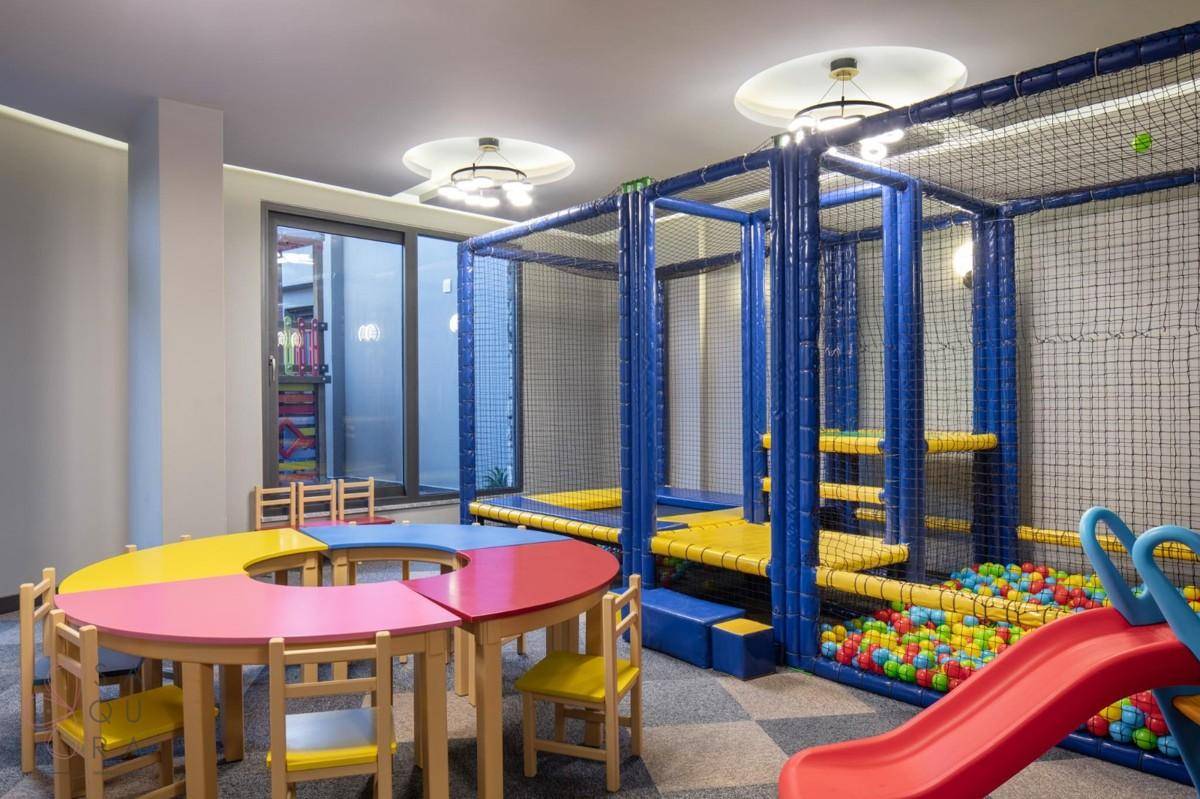 Farbenfroher Kinderspielbereich mit Bällebad, Rutsche und kleinen Tischen für kreative Aktivitäten.