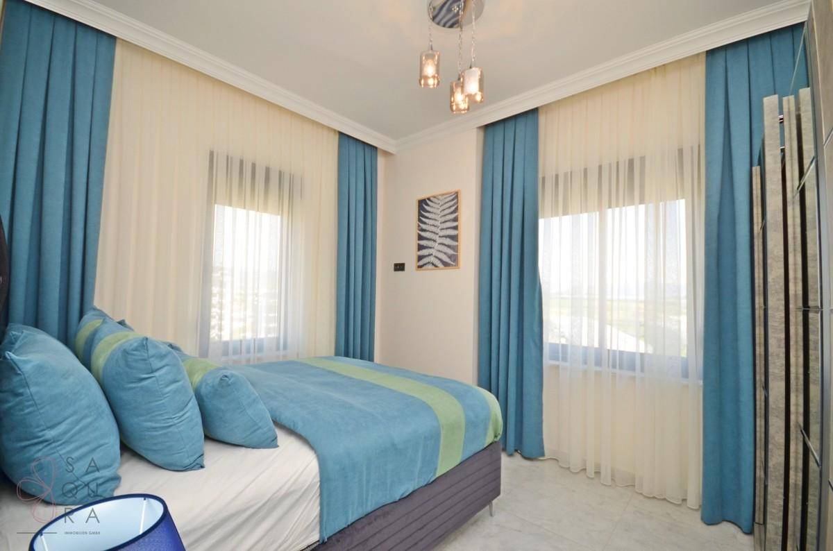 Schlafzimmer mit zwei Fenstern, Doppelbett und modernem Kleiderschrank.