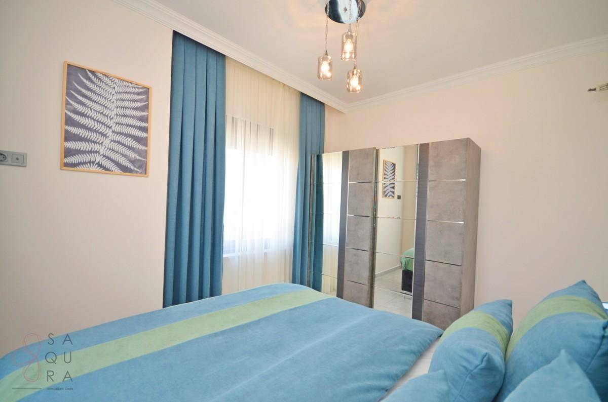 Gemütliches Schlafzimmer mit Doppelbett, Spiegelschrank und blauen Vorhängen.