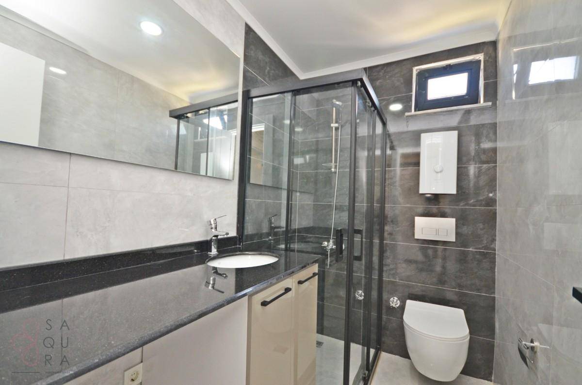 Modernes Badezimmer mit Duschkabine, Wand-WC, Einzelwaschbecken und Fenster.