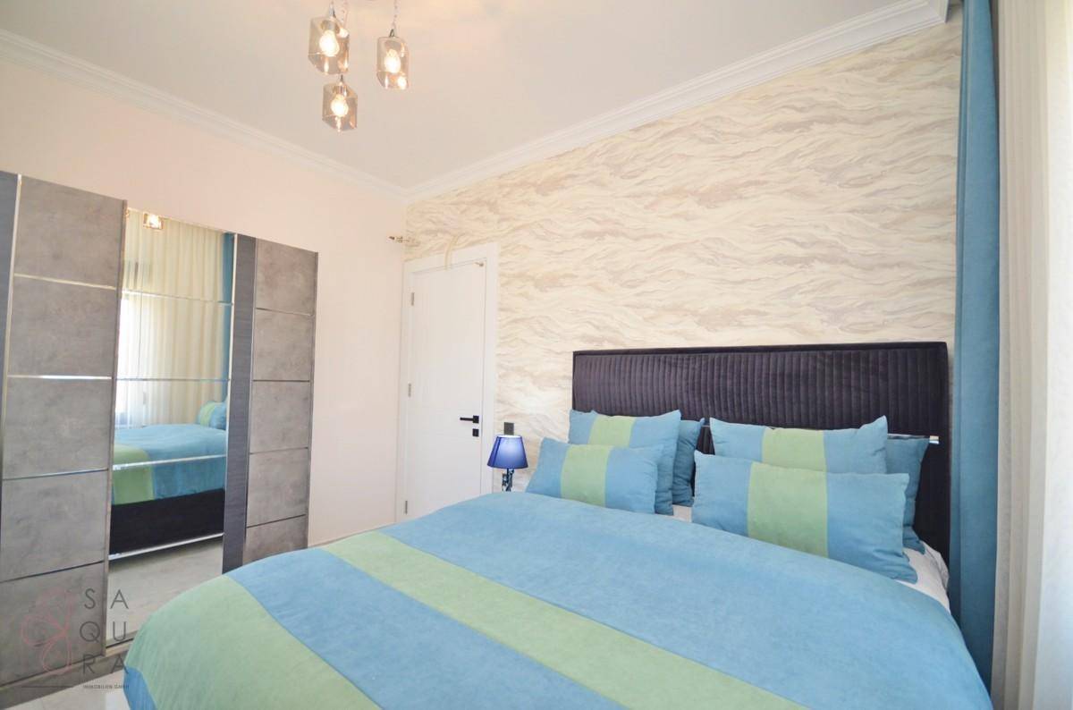 Helles Schlafzimmer mit Doppelbett, dekorativer Wandgestaltung und modernem Kleiderschrank.