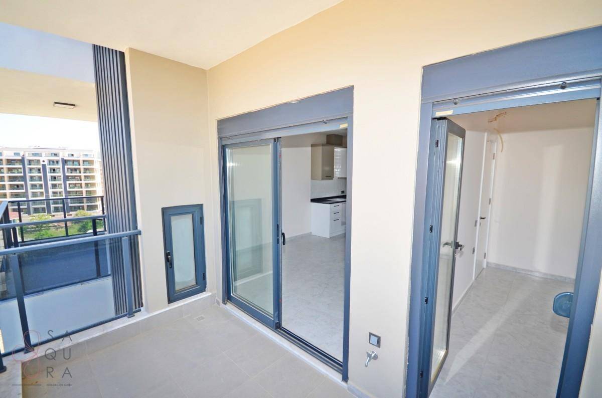 Heller Balkon mit Schiebetüren, der Zugang zu einem unmöblierten Innenraum bietet.