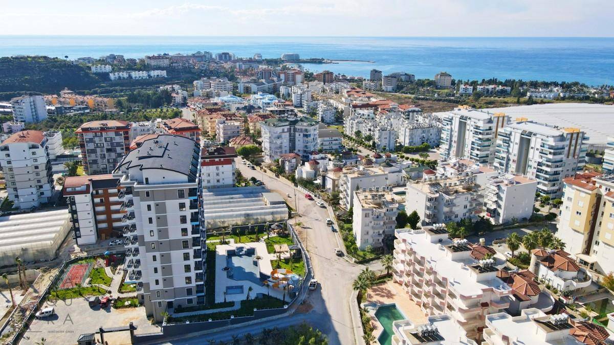 Weitläufiger Blick über die Küstenstadt mit zahlreichen Wohngebäuden und dem Mittelmeer.