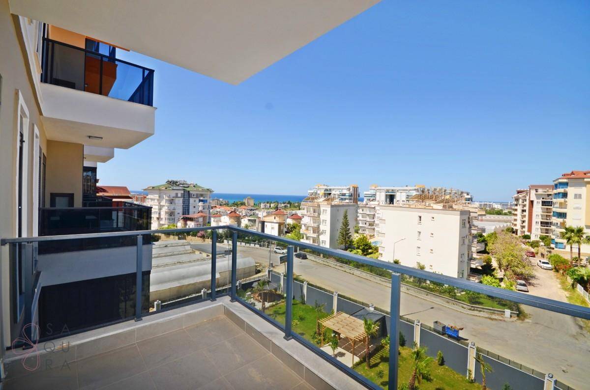 Geräumiger Balkon mit Glasgeländer und weitem Blick über die Stadt zum Meer.